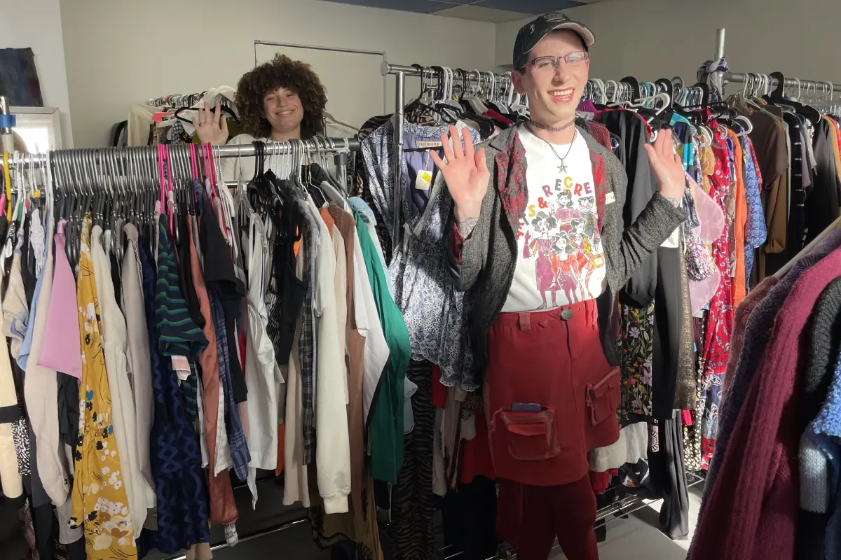 Two people wave between clothing racks inside Quirk’s free boutique.